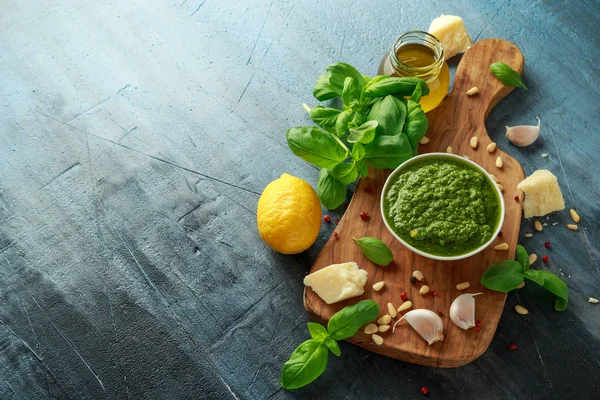 Pesto de manjericão verde com queijo parmesão, pinhões, alho e limão em tábua de madeira — Fotografia de Stock