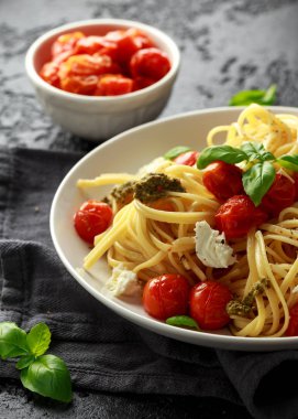 Yeşil pesto sos, Közlenmiş Domates ve mozzarella peyniri rustik koyu arka plan üzerinde beyaz plaka ile makarna