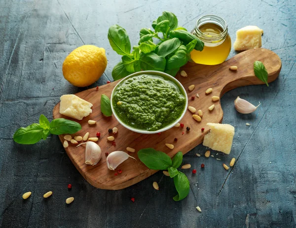 Pesto de manjericão verde com queijo parmesão, pinhões, alho e limão em tábua de madeira — Fotografia de Stock