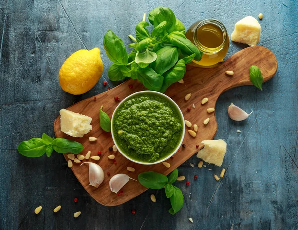 Pesto de manjericão verde com queijo parmesão, pinhões, alho e limão em tábua de madeira — Fotografia de Stock