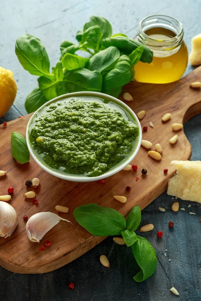 Pesto de manjericão verde com queijo parmesão, pinhões, alho e limão em tábua de madeira — Fotografia de Stock