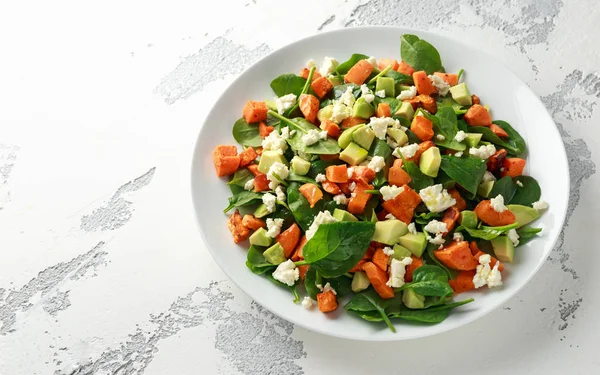 Авокадо, жареный сладкий картофель, шпинат, сыр фета здоровый салат в белой тарелке . — стоковое фото