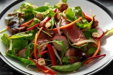 Havuç, turp, fasulye filizi, biber, fındık ve yeşil karışımı ile baharatlı biftek salatası