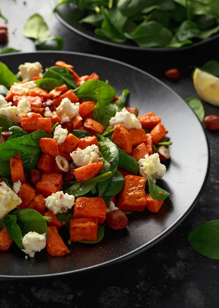 Frisk ristet søtpotetsalat med spinat, fetaost, hasselnøtter i svart tallerken – stockfoto