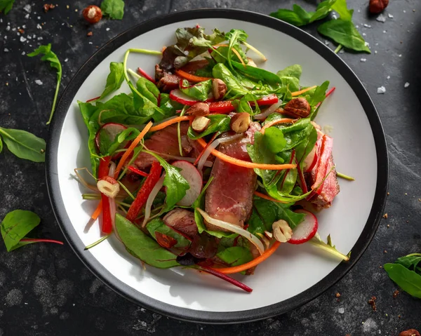 Havuç, turp, fasulye filizi, biber, fındık ve yeşil karışımı ile baharatlı biftek salatası