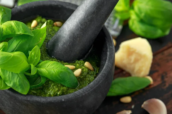 Green Basil Pesto em argamassa de mármore com queijo parmesão, pinhões, alho e limão . — Fotografia de Stock