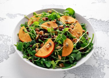 Trabzon hurması ve bezelye salatası ceviz, nar ve kabak çekirdeği beyaz bir tablo içinde ateş