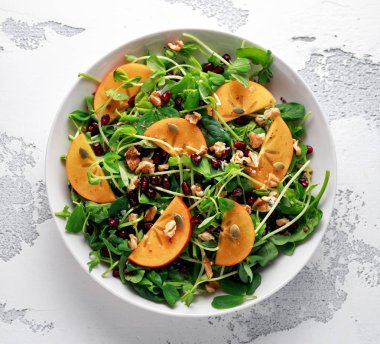 Trabzon hurması ve bezelye salatası ceviz, nar ve kabak çekirdeği beyaz bir tablo içinde ateş