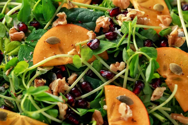 Gustosa insalata di cachi e piselli con noci, melograno e semi di zucca in un piatto bianco — Foto Stock