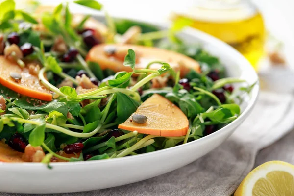 Lezzetli Trabzon hurması ve bezelye salatası ceviz, nar ve kabak çekirdeği beyaz bir tabak içinde ateş