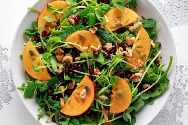 Trabzon hurması ve bezelye salatası ceviz, nar ve kabak çekirdeği beyaz bir tablo içinde ateş