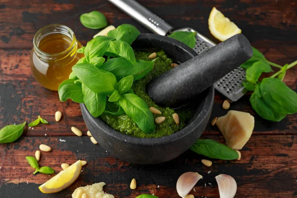 Green Basil Pesto em argamassa de mármore com queijo parmesão, pinhões, alho e limão . — Fotografia de Stock