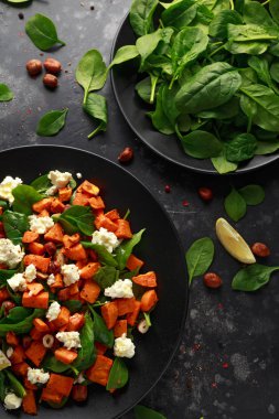 Ispanak, beyaz peynir, siyah plaka içinde fındık fındık ile sağlıklı kavrulmuş patates salatası