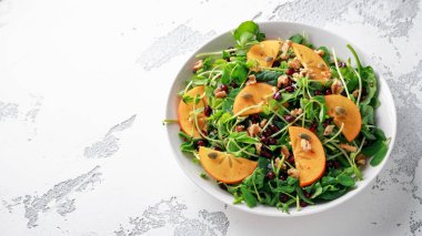 Trabzon hurması ve bezelye salatası ceviz, nar ve kabak çekirdeği beyaz bir tablo içinde ateş