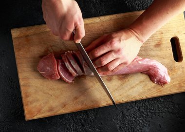 Kasaplar ellerini ahşap tahta üzerinde bir bıçak Çiğ domuz eti bonfile fileto ile kesmeye hazır.