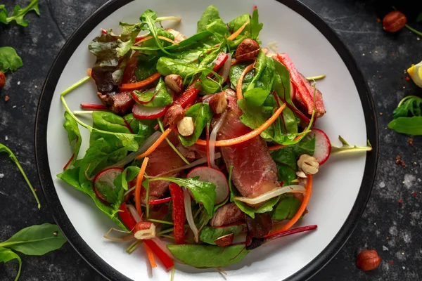 Havuç, turp, fasulye filizi, biber, fındık ve yeşil karışımı ile baharatlı biftek salatası