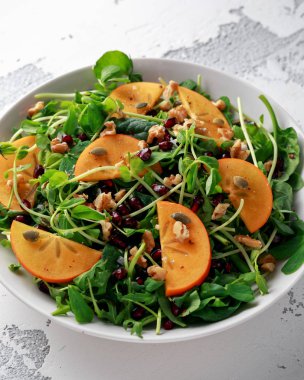 Trabzon hurması ve bezelye salatası ceviz, nar ve kabak çekirdeği beyaz bir tablo içinde ateş