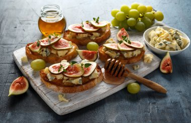 Bu Gorgonzola ve incir tartines, tost, bruschetta. Beyaz ahşap tahta üzerinde bal ile drizzled