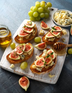 Bu Gorgonzola ve incir tartines, tost, bruschetta. Beyaz ahşap tahta üzerinde bal ile drizzled