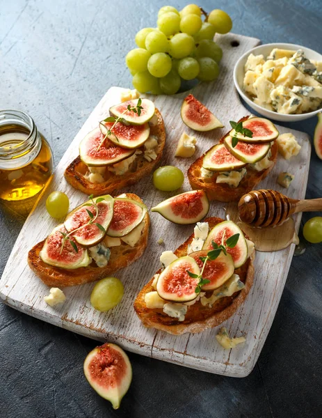 Bu Gorgonzola ve incir tartines, tost, bruschetta. Beyaz ahşap tahta üzerinde bal ile drizzled