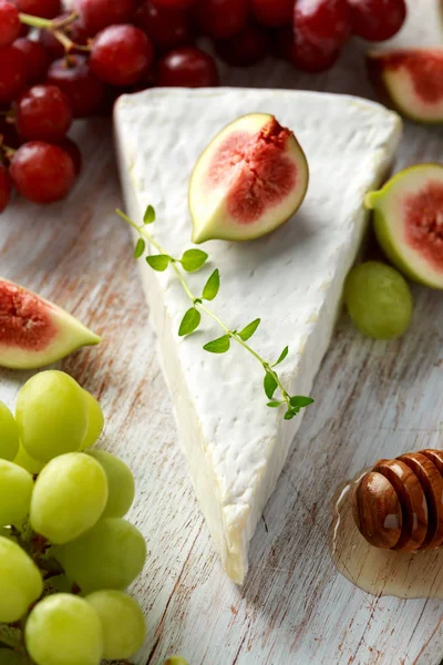 Peynir brie incir, yeşil ve kırmızı üzüm ve ballı Beyaz ahşap tahta üzerinde