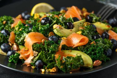 Somon Kale süper yiyecek salata avokado, Antep fıstığı ve siyah plaka üzerinde yaban mersini