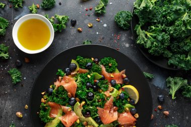 Somon Kale süper yiyecek salata avokado, Antep fıstığı ve siyah plaka üzerinde yaban mersini