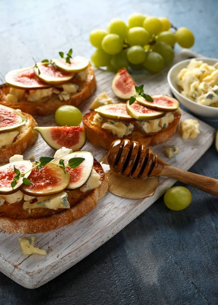 Bu Gorgonzola ve incir tartines, tost, bruschetta. Beyaz ahşap tahta üzerinde bal ile drizzled