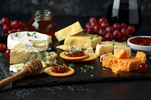 Cheese platter served with grapes, ale chutney, honey, crackers on stone board. Brie, cheddar, red leicester, wensleydale cranberries, blue stilton.