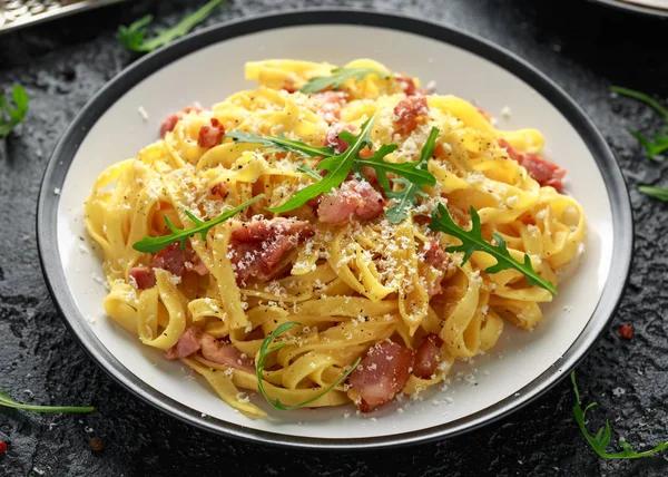 Pasta Carbonara clásica, espaguetis con panceta, tocino, huevo, queso parmesano y rúcula verde . — Foto de Stock