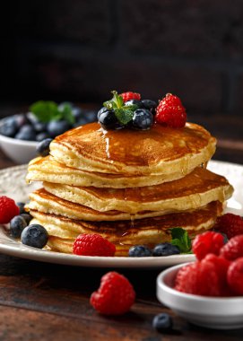 Ev yapımı Amerikan krep taze yaban mersini, ahududu ve bal ile. Sağlıklı sabah kahvaltı. rustik tarzı