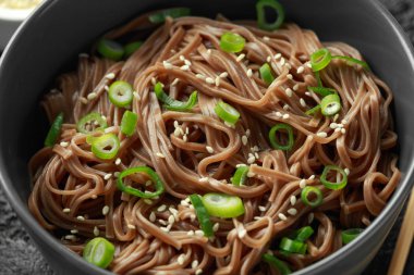 Soba noodle, taze soğan ve susam ile siyah bir kase üzerinde buğday. Geleneksel Japon yemekleri.