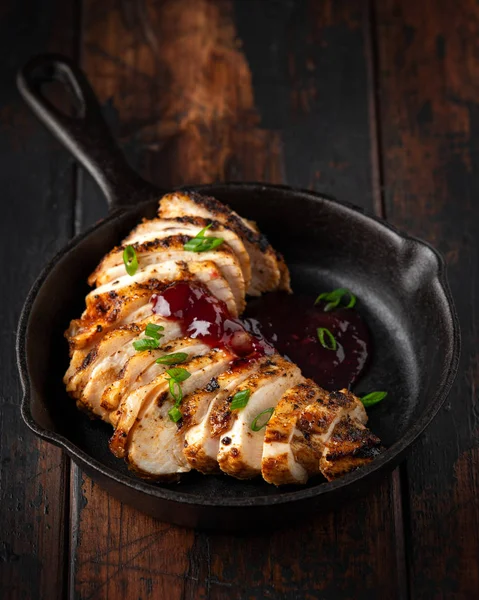 Жареная нарезанная куриная грудка с клюквенным соусом в мини чугунной сковородке — стоковое фото