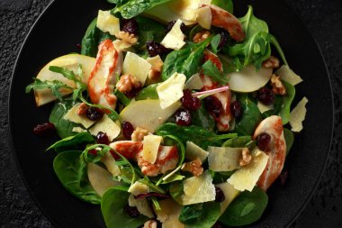 Armut, kaşar peyniri, kızılcık ve ceviz tavuk salatası. sağlıklı gıda. siyah taş zemin