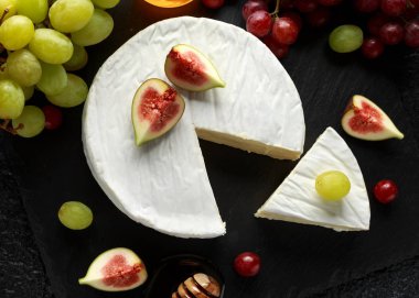 Beyaz taş tabak brie incir, yeşil ve kırmızı üzüm ile peynir ve bal.