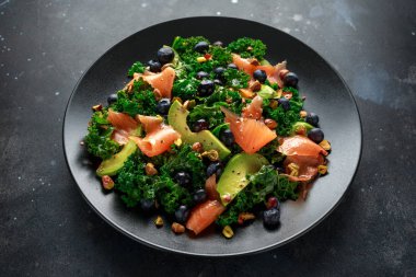 Somon Kale süper yiyecek salata avokado, Antep fıstığı ve siyah plaka üzerinde yaban mersini