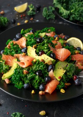 Somon Kale süper yiyecek salata avokado, Antep fıstığı ve siyah plaka üzerinde yaban mersini