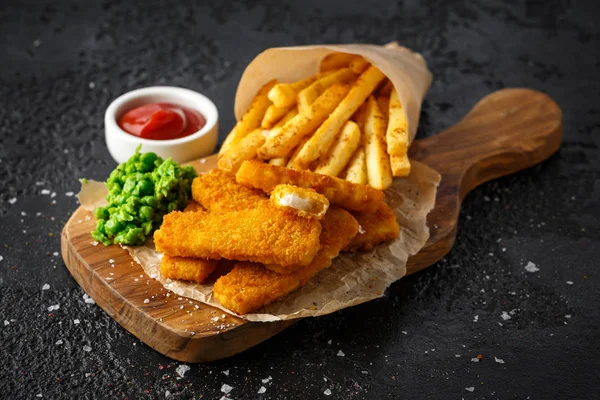 Fiskpinnar, mosade ärtor och chips frites. Traditionella brittiska snabbmat — Stockfoto