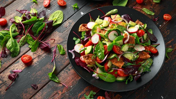 Традиційний салат на тарілці з грінками піта, огірком, помідорами, червоною цибулею, овочами та травами — стокове фото