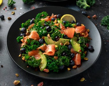 Somon Kale süper yiyecek salata avokado, Antep fıstığı ve siyah plaka üzerinde yaban mersini