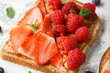 Fıstık ezmesi sandviç taze çilek, yaban mersini, ahududu ve muz yemek tost ile.