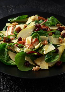 Armut, kaşar peyniri, kızılcık ve ceviz tavuk salatası. sağlıklı gıda. siyah taş zemin