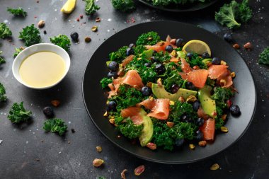Somon Kale süper yiyecek salata avokado, Antep fıstığı ve siyah plaka üzerinde yaban mersini