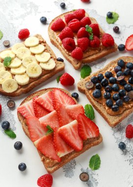Fıstık ezmesi sandviç taze çilek, yaban mersini, ahududu ve muz yemek tost ile.