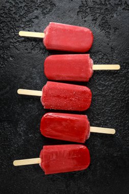 Ev yapımı ahududu çubuklu dondurmayı, Buz lolly rustik siyah arka plan üzerine