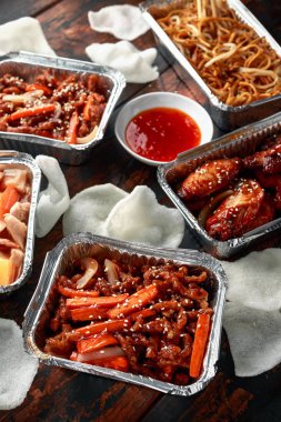 Chinese takeaway food. Crispy shredded beef, sweet and sour chicken wings, egg noodles with bean sprouts, pineapple, chilli dip and prawn crackers clipart