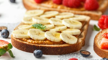 Fıstık ezmesi sandviç taze çilek, yaban mersini, ahududu ve muz yemek tost ile.