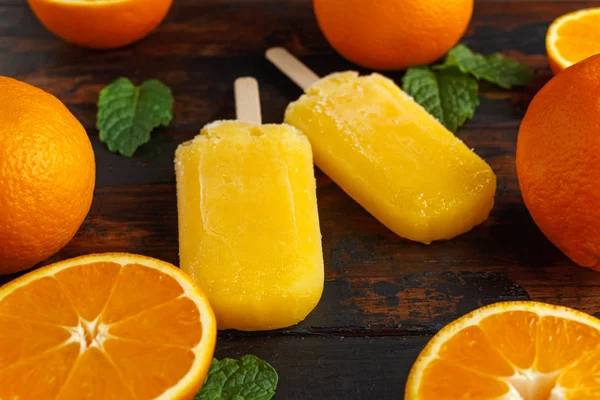 Homemade orange popsicles, ice lolly, on wooden table. Summer food.