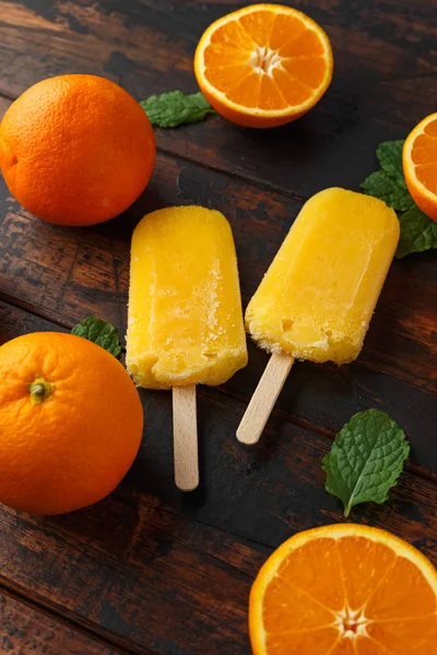 Picolés de laranja caseiros, gelados, na mesa de madeira. Comida de verão . — Fotografia de Stock