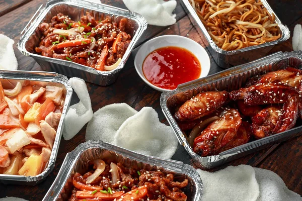 Chinese takeaway food. Crispy shredded beef, sweet and sour chicken wings, egg noodles with bean sprouts, pineapple, chilli dip and prawn crackers